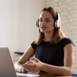 Focused businesswoman wearing headset looking at laptop screen and talking